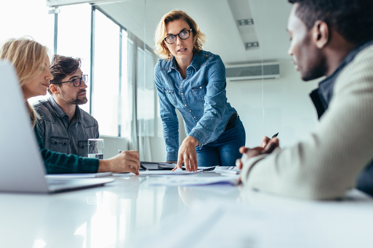 Businesswoman leading business presentation | Marketing Direction | Digital Marketing Agency | Tampa - St Pete FL Marketing leader directing team discussion over strategic documents, demonstrating the human interpretation layer AI cannot replace